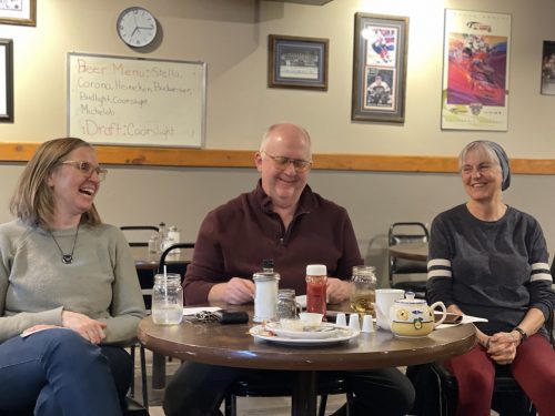 Cheryl, Tom and Earleen at a round pub table with food